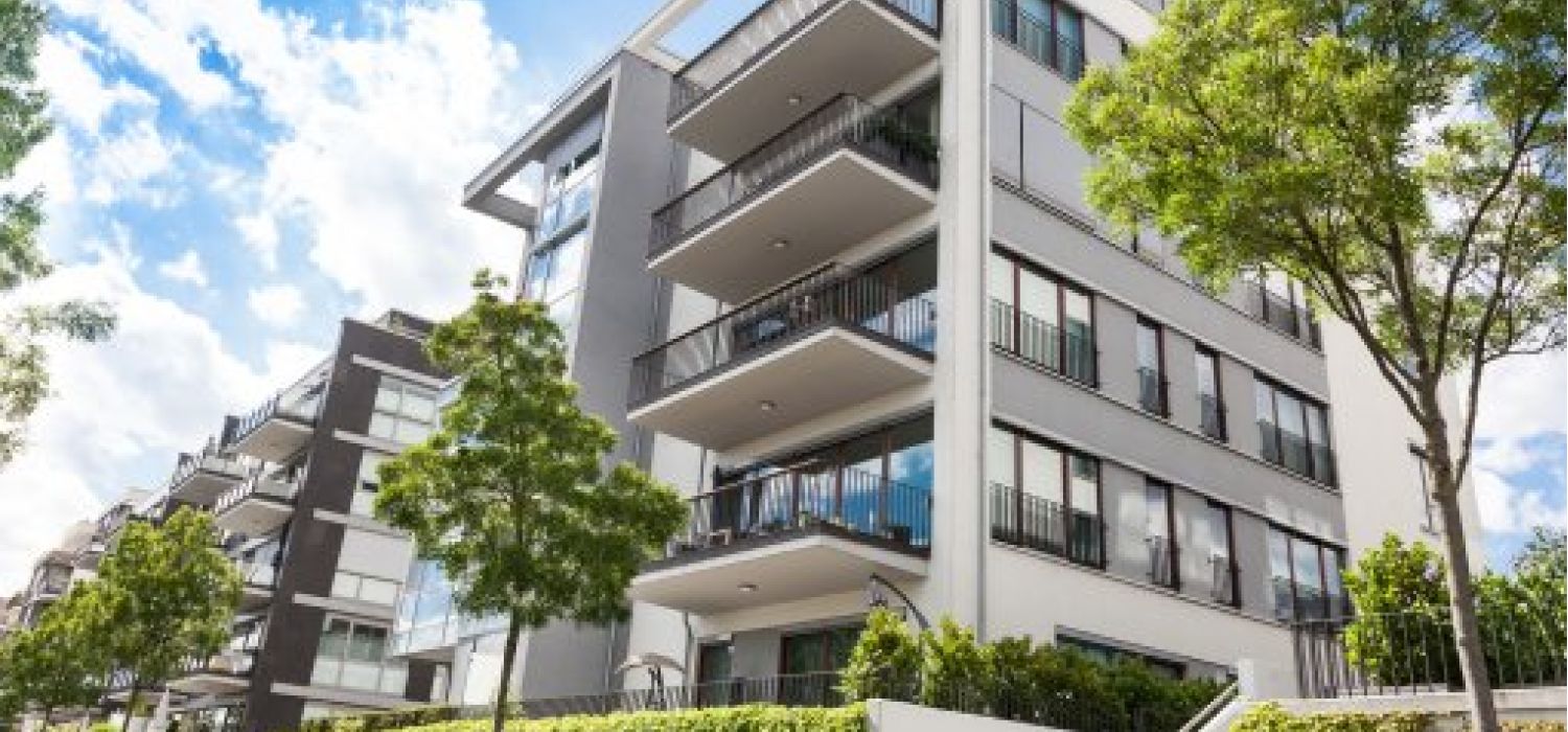 Facciata di un moderno condominio residenziale con balconi aggettanti, ampie vetrate e verde circostante